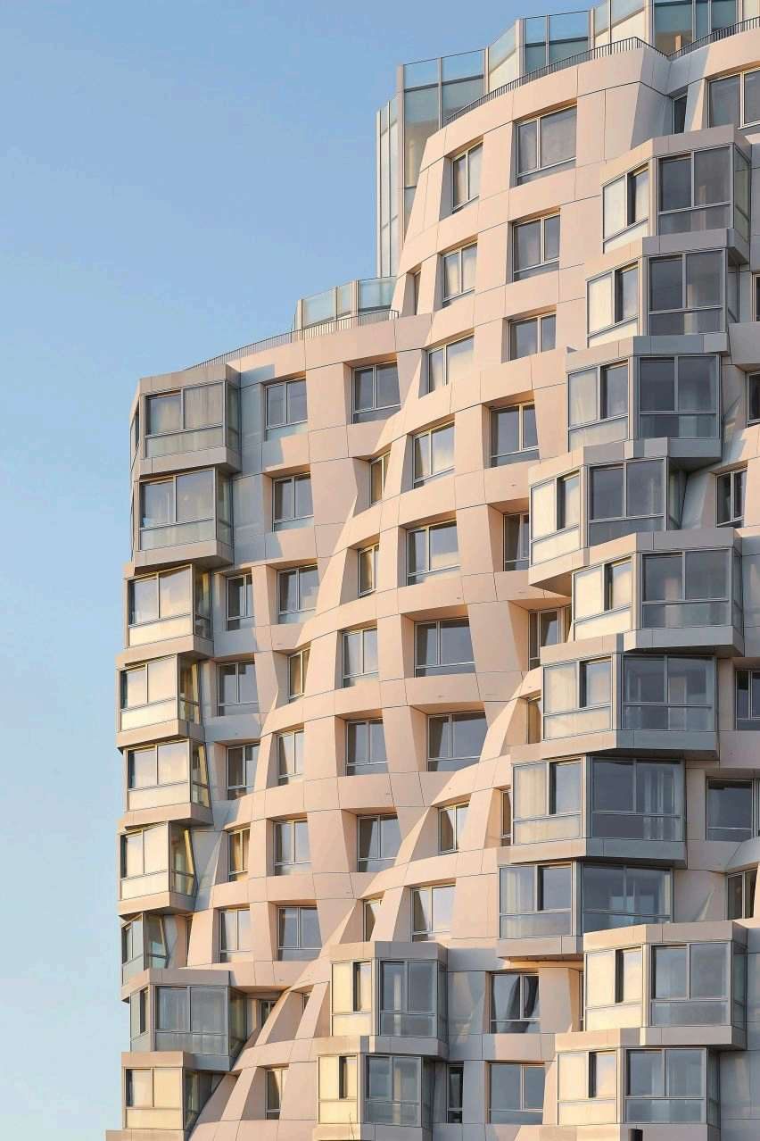 Electric Boulevard's sculpted residential facade with staggered balconies against a clear sky